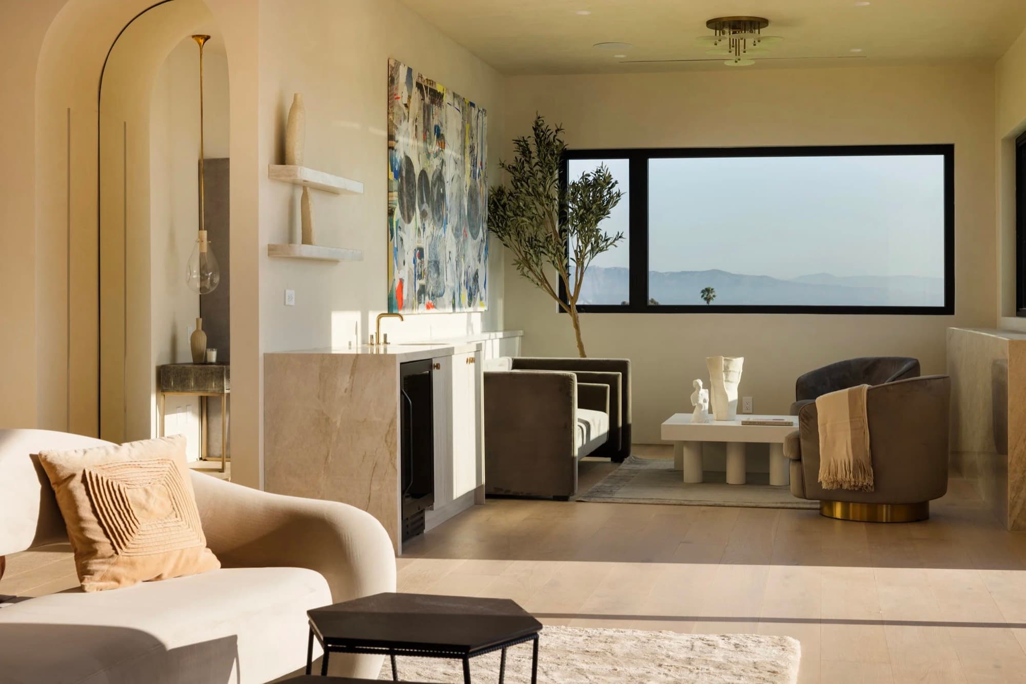 A large abstract painting placed in a living room facing a hillside view